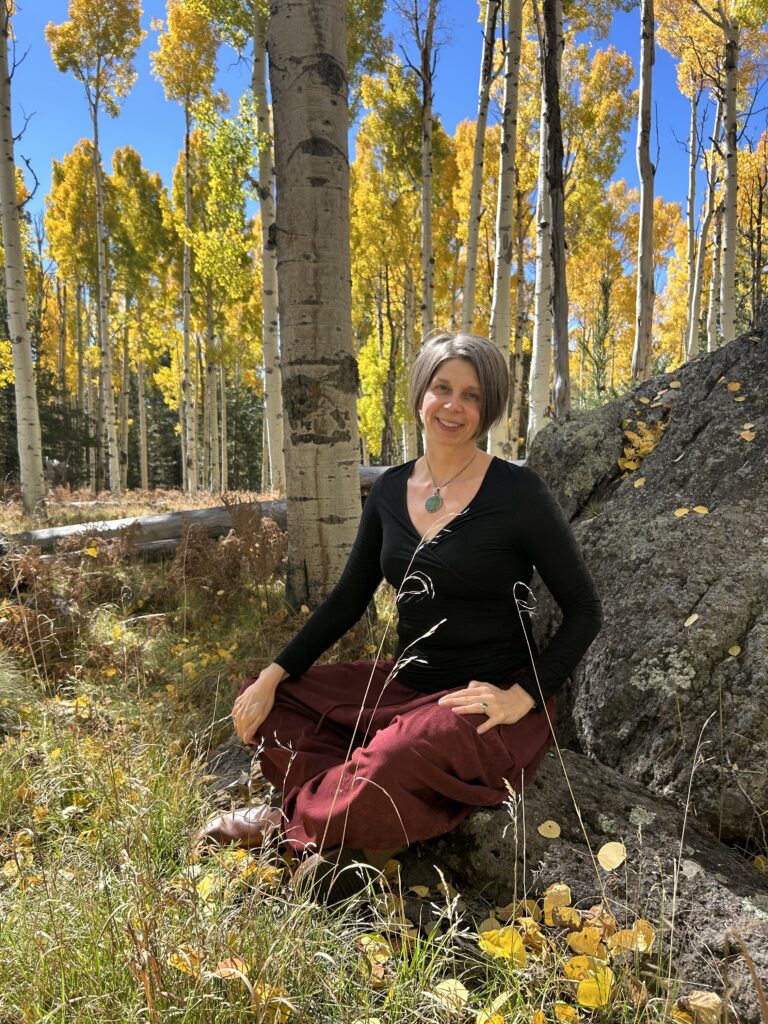 Joy Bauer sitting in an aspen forest with hands resting in her lap